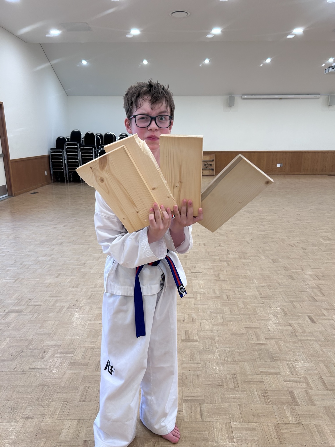Impact student proudly holding boards after a successful break