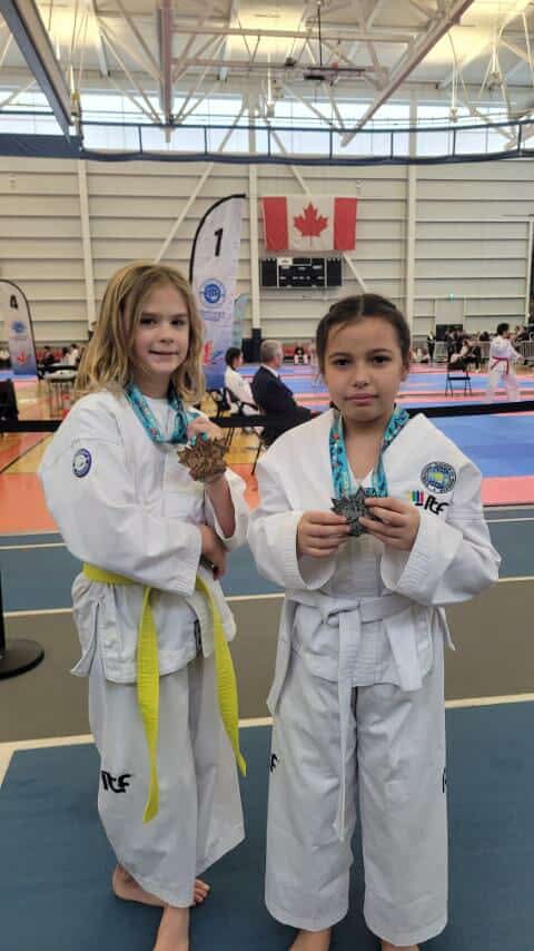 Two young Impact martial artists holding competition medals