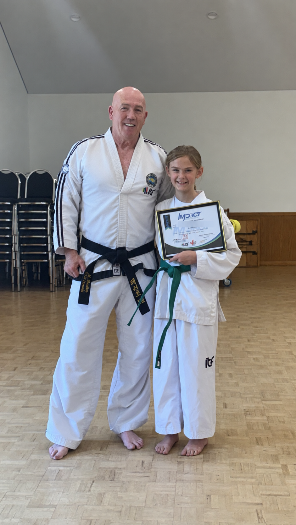 Master Michael Barker with a student and her achievement certificate with identifying details blurred